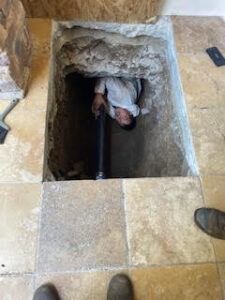 Plumber repairing sewer main under a home in glendora